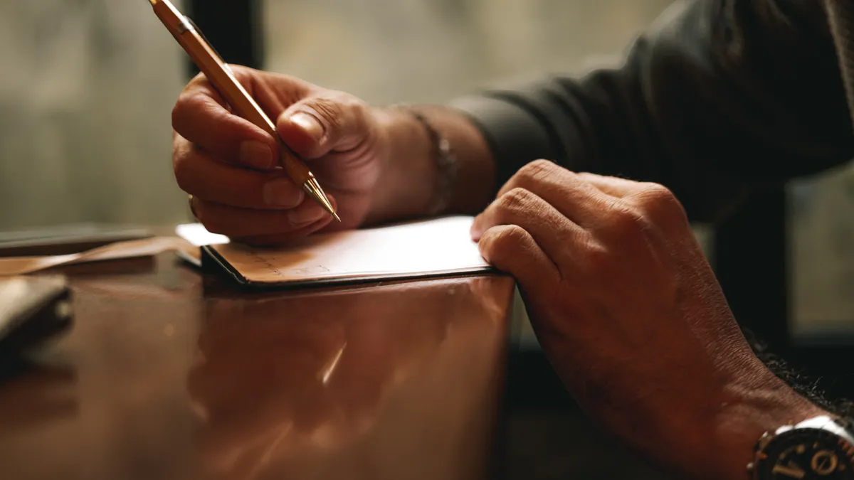 AI content writing tools vs human content writers — Close-up of Hands Writing with Pen on Desk
