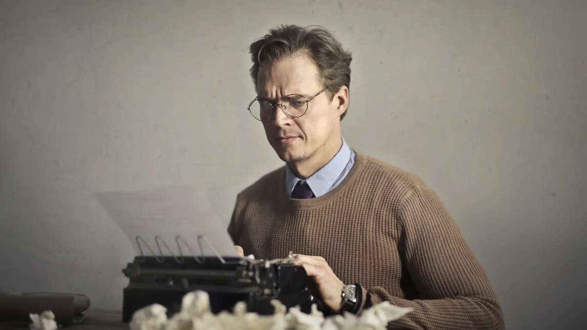 Freelance writer vs content writing agency: which should you hire? — Adult frowned male writer working on typewriter at 