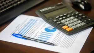 calculator with pen and financial charts on desk