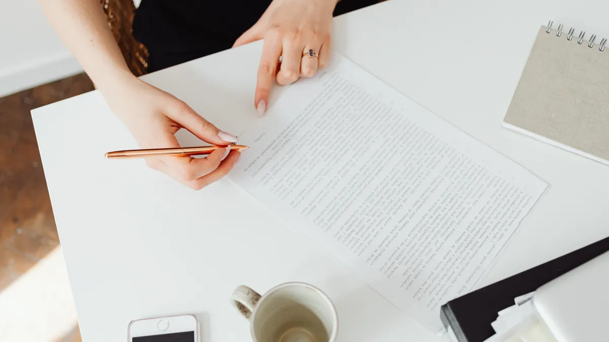 Hands reading and annotating a printed document