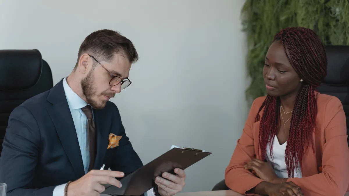 Hiring interview with a candidate and interviewer reviewing a clipboard
