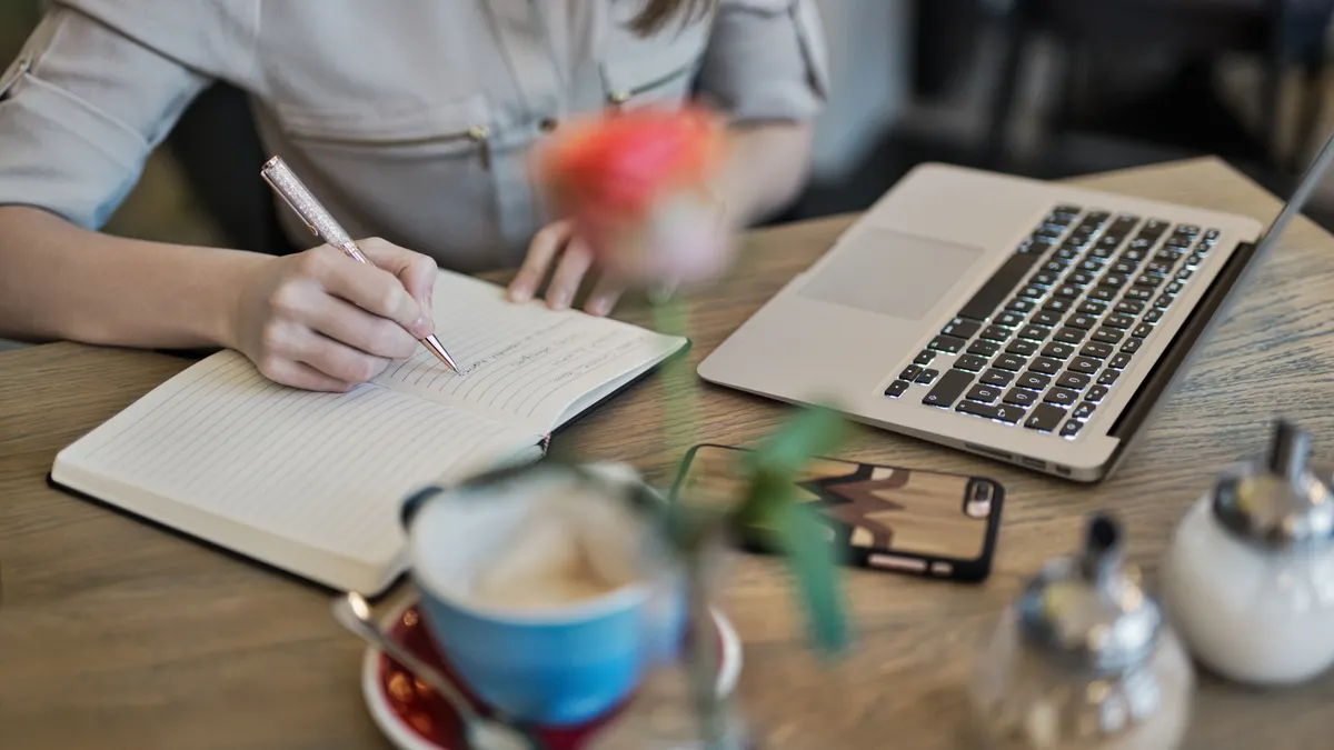 Questions to ask before hiring a content writer — Person Writing On A Notebook Beside Macbook