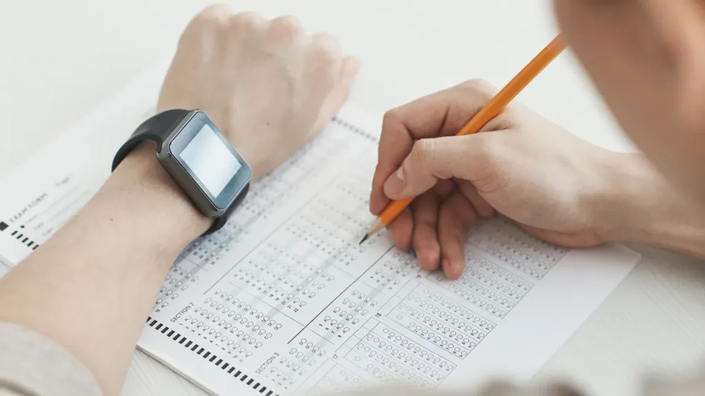 Hands filling out a multiple-choice test sheet