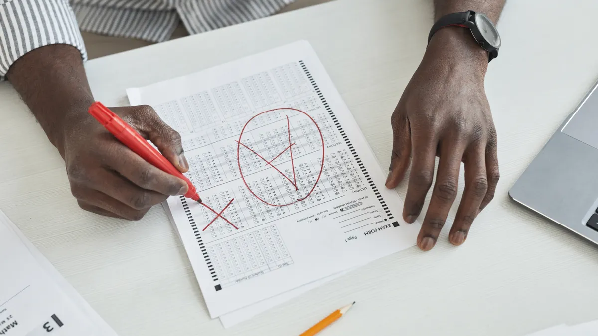Hands marking a test sheet with a red pen