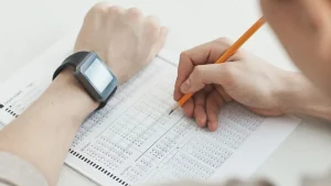 Hands filling out a multiple-choice test sheet