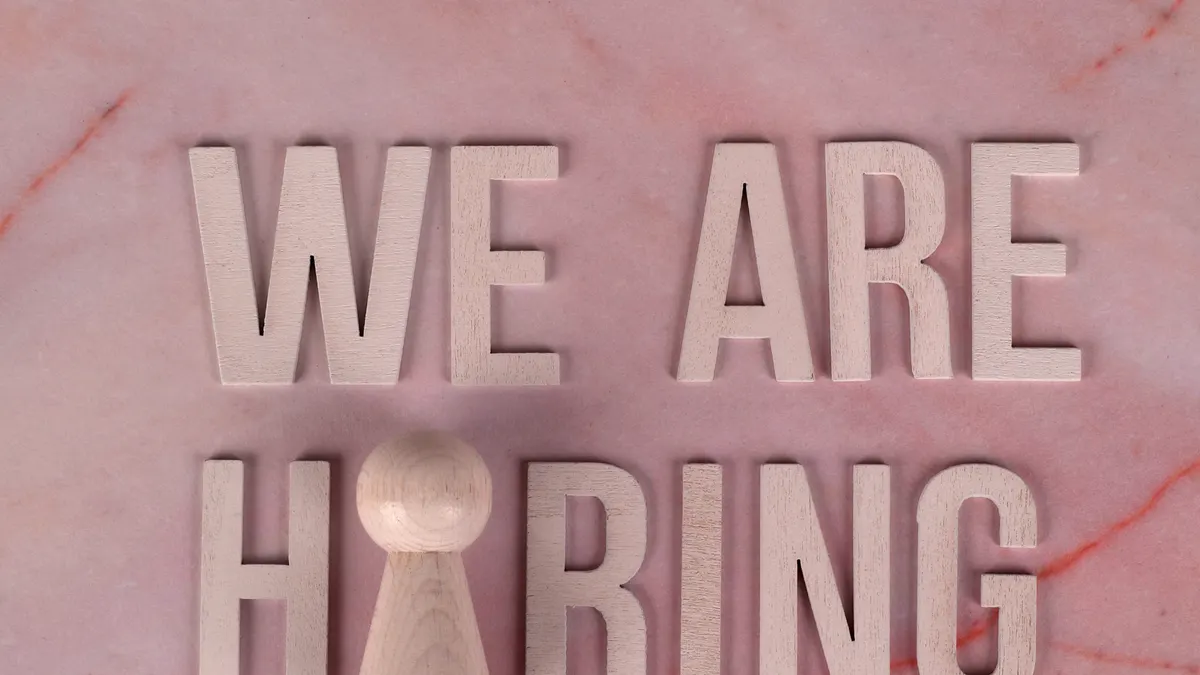What to look for when hiring a content writer — We Are Hiring Sign on Pink Marble Background